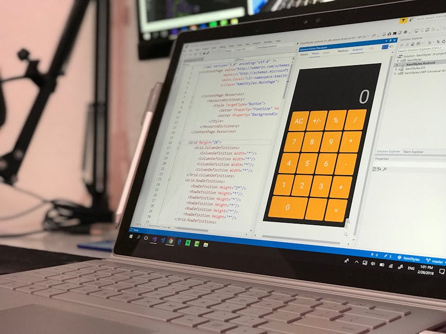 A close-up view of a laptop screen situated on a desk, displaying lines of computer code in a development environment on the left and a large, orange calculator widget on the right with a black backgr